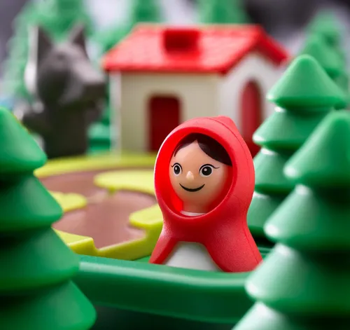 alt="Figurka Czerwonego Kapturka - postać z gry logicznej Smart Games Czerwony Kapturek, umieszczona na plastikowej planszy ze ścieżką do domu Babci"